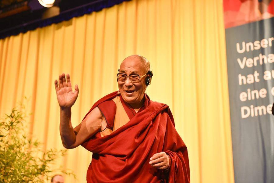 Dalai Lama waves to the audience at the end of his talk at the Congress Centre in Hamburg, Germany, on 23 August 2014.