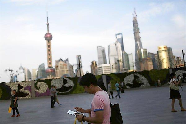 A man checks his iPad on the Bund in front of the financial district in Shanghai