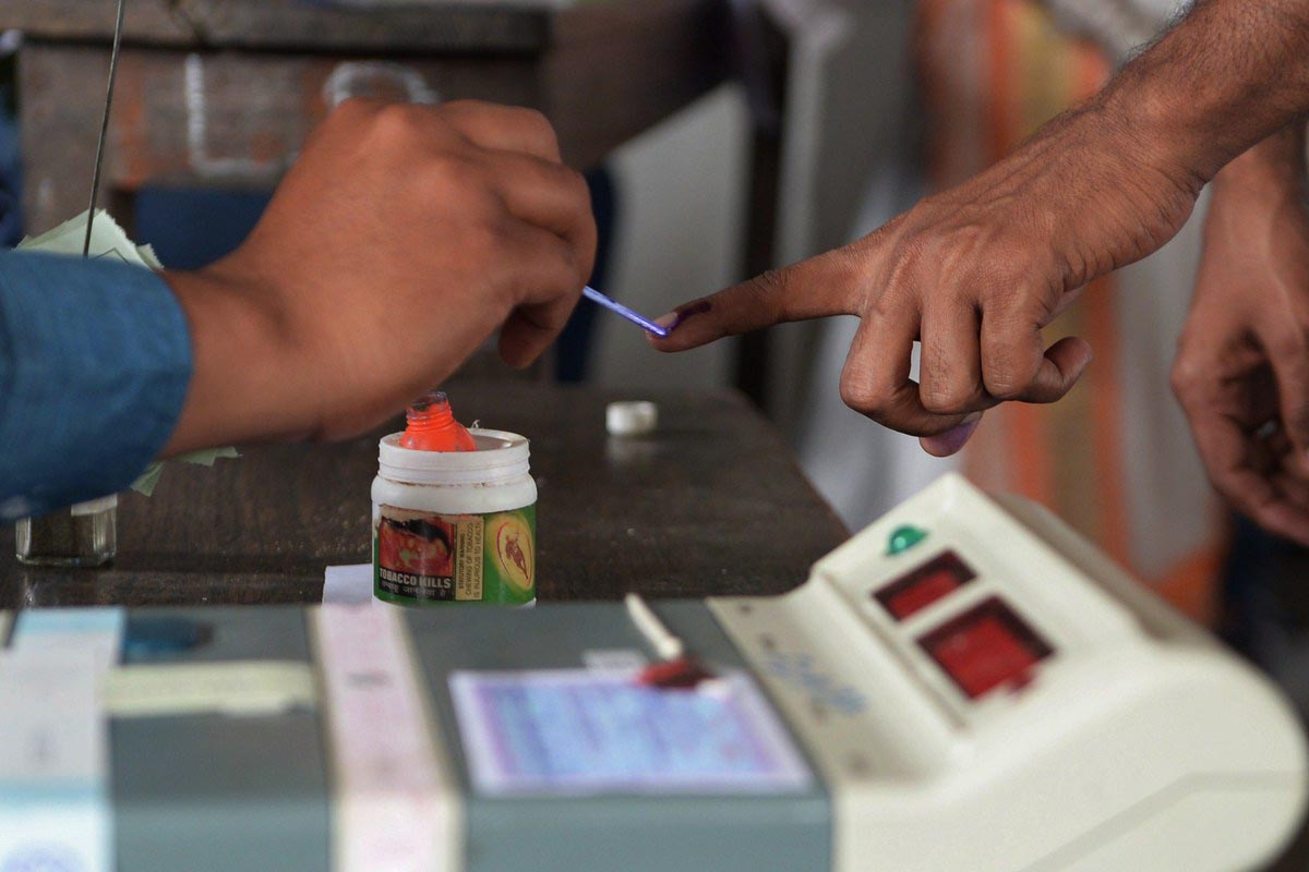 An election officer uses ink to mark a voter's finger at a polling station in Dibrugarh