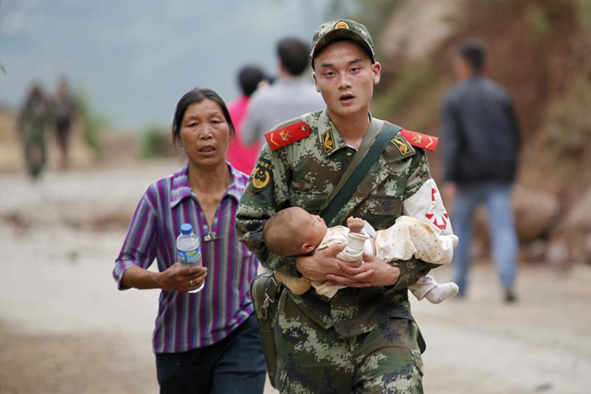 A paramilitary policeman carries a baby in his arms after an earthquake hit Ludian county of Zhaotong