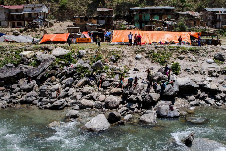 Local residents, displaced by an earthquake, gather alongside makeshift shelters on the banks of a river in Singati, on 5 May 2015.