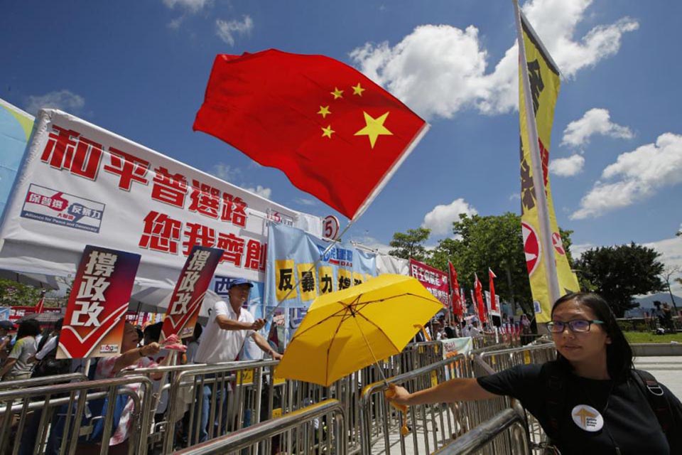 A pro-Beijing protester, left, holding a Chinese national flag confronts with a pro-democracy protester who is carrying a yellow umbrella outside the Legislative Council in Hong Kong, on 17 June 2015.