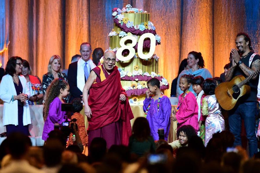 The Dalai Lama reacts as his birthday cake is wheeled out on stage following a performance for him by children at the Honda Center in Anaheim, California, on 5 July 2015.