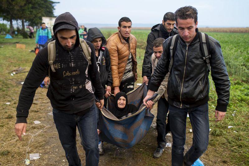 Migrants carry an elderly woman as they walk on a field, after they crossed the border with Serbia, near Tovarnik, Croatia, on 24 September 2015.