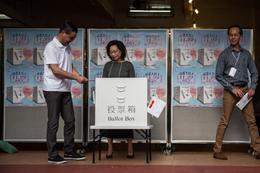 Hong Kong's Chief Executive Leung Chun-ying (L) casts his vote for the district council elections as his wife Regina Tong (C) watches at a polling station in the Central district of Hong Kong on 22 November 2015.