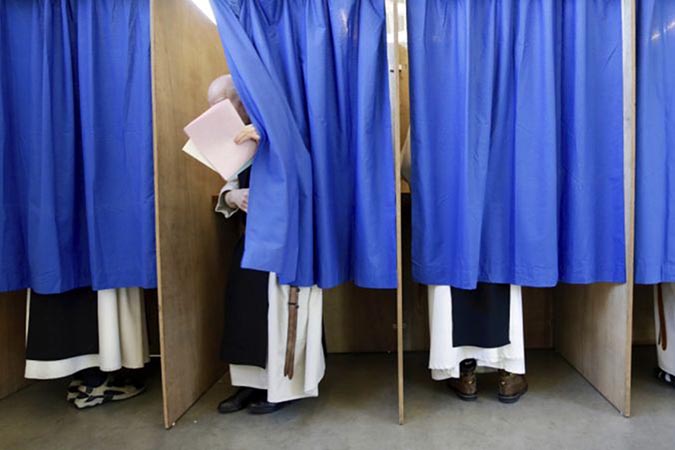 Monks from the Saint Sixtus Trappist Abbey cast their votes behind curtains at a polling station in Westvleteren, Belgium, on 26 May 2019. Belgium, which has one of the oldest compulsory voting systems, goes to the polls Sunday to vote on the regional, federal and European level.