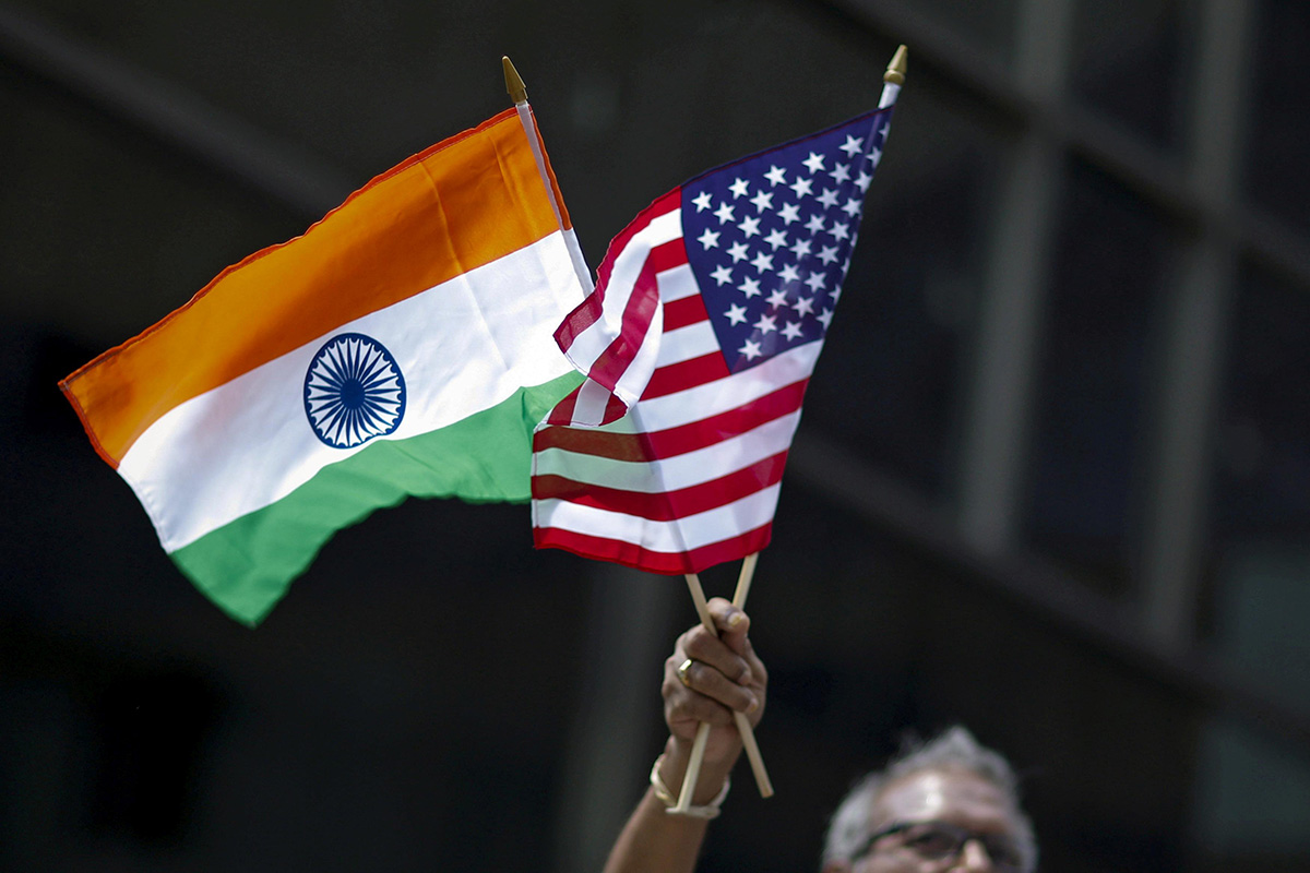 A man holds the flags of India and the US while people take part in the 35th India Day Parade in New York, on 16 August 2015.
