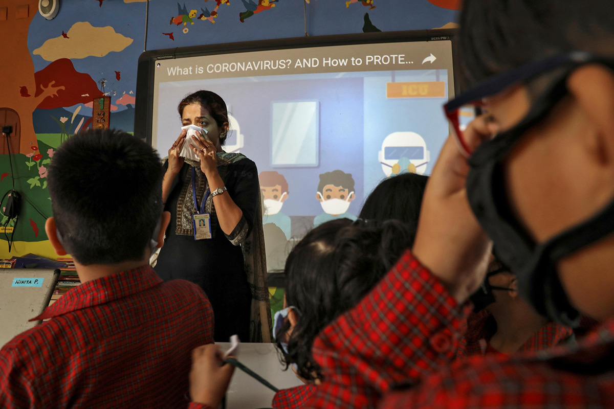A teacher demonstrates as students wearing protective masks attend a coronavirus awareness campaign lecture at a school in Kolkata, India, on 6 March 2020.