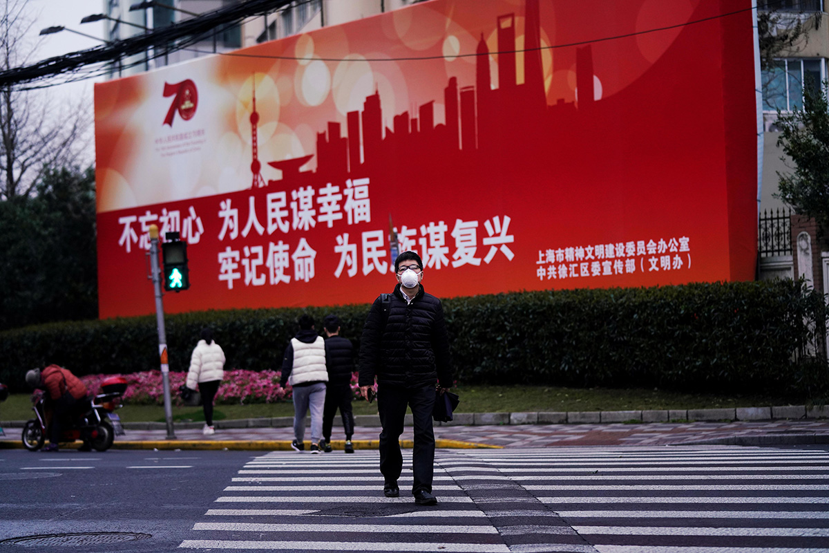 A man wearing a face mask walks across a road as the country is hit by an outbreak of the novel coronavirus COVID-19, in Shanghai, China, on 9 March 2020.