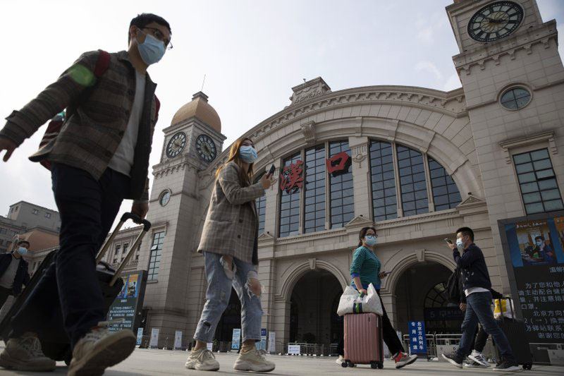 Travellers with their luggage walk past the Hankou railway station on the eve of its resuming outbound traffic in Wuhan in central China's Hubei province on 7 April 2020. Starting Wednesday, residents of Wuhan will be allowed to once again travel in and out of the sprawling city where the coronavirus pandemic began, ending an 11-week lockdown.