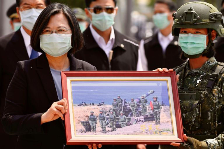 Taiwan President Tsai Ing-wen receives a framed photograph from a masked soldier during the COVID-19 coronavirus pandemic during a visit to a military base in Tainan on 9 April 2020.