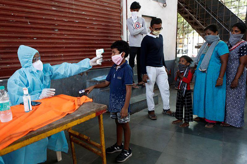 A healthcare worker checks a boy's temperature with an infrared thermometer at a camp in Dharavi, one of Asia's largest slums, during an extended lockdown to slow the spread of the coronavirus disease (COVID-19), India, on 29 May 2020.