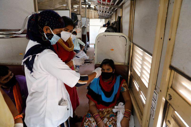 A health worker checks the temperature of a passenger inside a train, after a limited reopening of India's giant rail network following a nearly seven-week lockdown to slow the spreading of the coronavirus disease (COVID-19), in Greater Noida, India, on 16 May 2020.