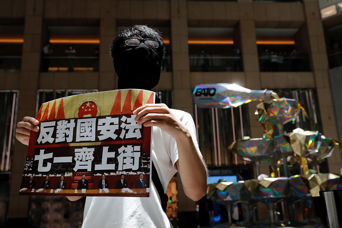 A pro-democracy protester holds a placard that reads ''Against the national security law. March on July 1'' during a protest after China's parliament passes a national security law for Hong Kong, in Hong Kong, China, on 30 June 2020.