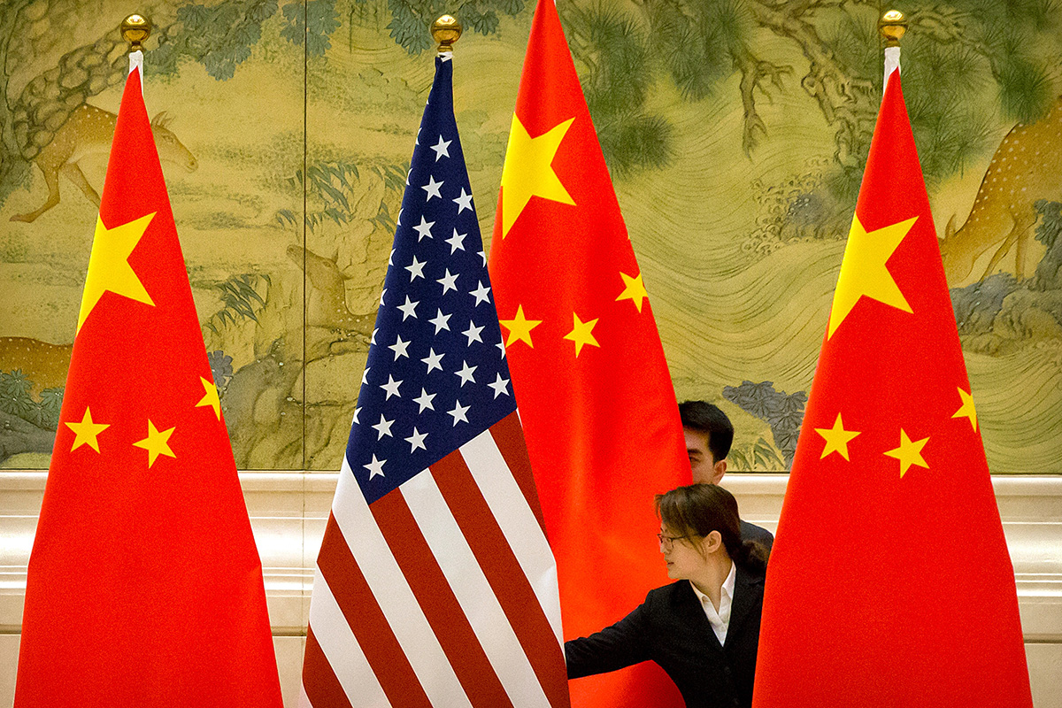 Chinese staffers adjust US and Chinese flags before a session of negotiations between US and Chinese trade representatives, at the Diaoyutai State Guesthouse, in Beijing, China, on 14 February 2019.