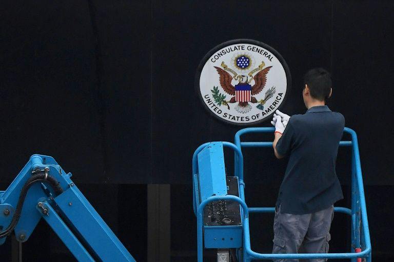 A worker removes the Great Seal of the United States from the front of the US consulate in the Chinese city of Chengdu on Saturday.