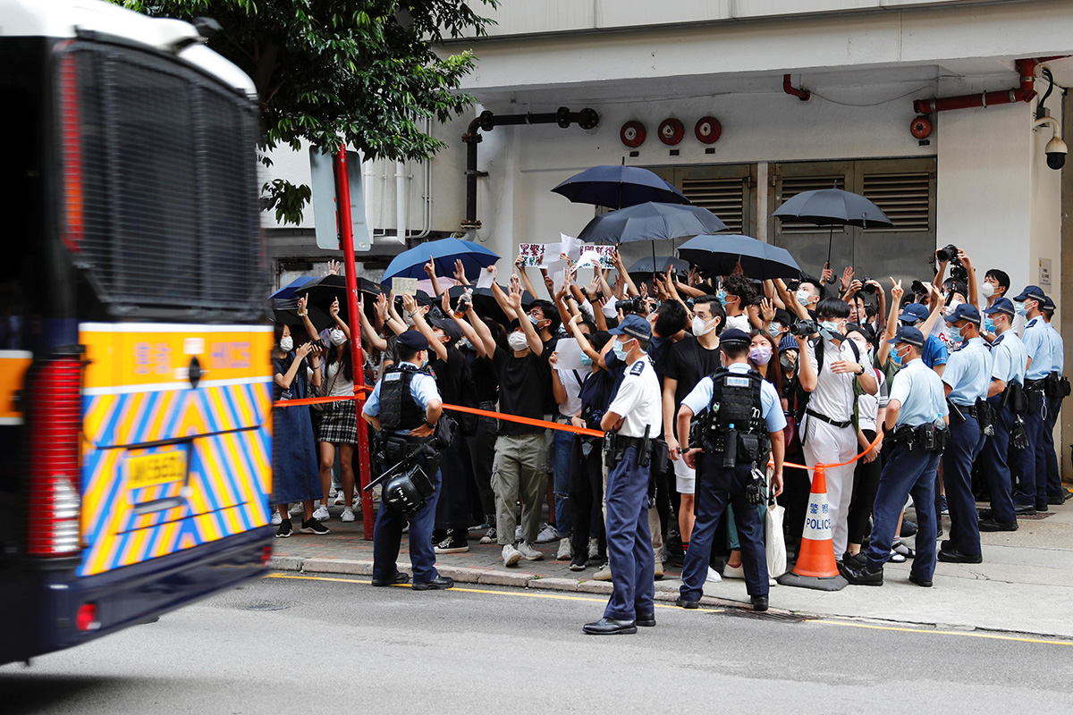 Supporters raise white paper to avoid slogans banned under the national security law as they support arrested anti-law protester, as a prison van leaves Eastern court in Hong Kong, China, on 3 July 2020.