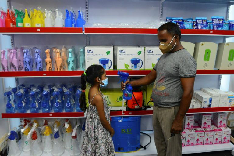 A storekeeper shows to a child a fan-sprinkler used for spraying disinfectant, at a shop selling products against the spread of Covid-19 in Vallabh Vidyanagar, 65km from Ahmedabad, India.