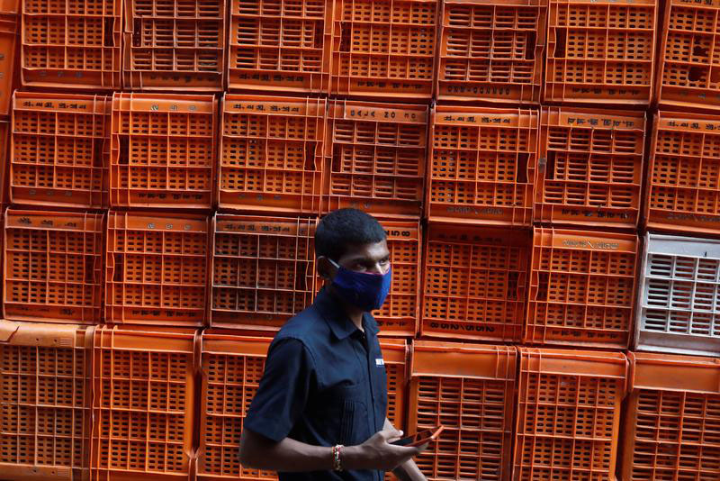 A man wearing a protective mask walks past baskets stacked at a flower market amidst the spread of the coronavirus disease (COVID-19), in Mumbai, India, on 20 October 2020.