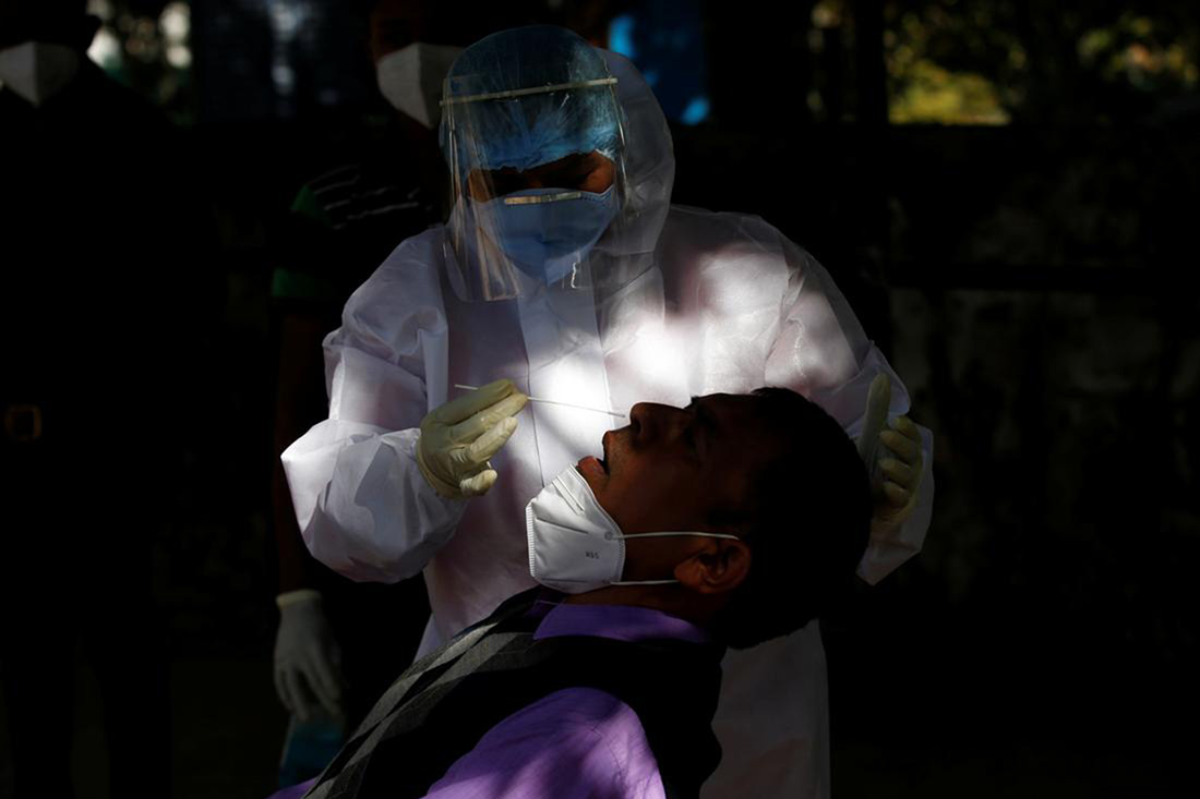 A healthcare worker wearing personal protective equipment (PPE) collects a swab sample from a Border Security Force (BSF) soldier during a rapid antigen testing campaign for the coronavirus disease (COVID-19), in Gandhinagar, India, on 29 December 2020.