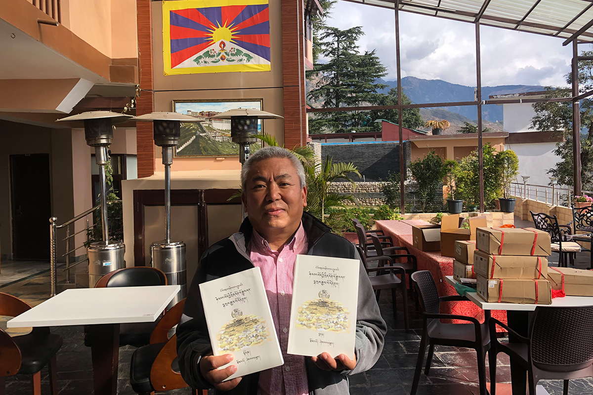 Author Sherab Dhargye stands with his two-volume work titled 'Modern Political History of Tibet and Gyalo Thondup's Work - Setting the record straight and unveiling the hidden' in Tibetan language, after its launch at Norbu House, McLeod Ganj, India, on 5 December 2020. 