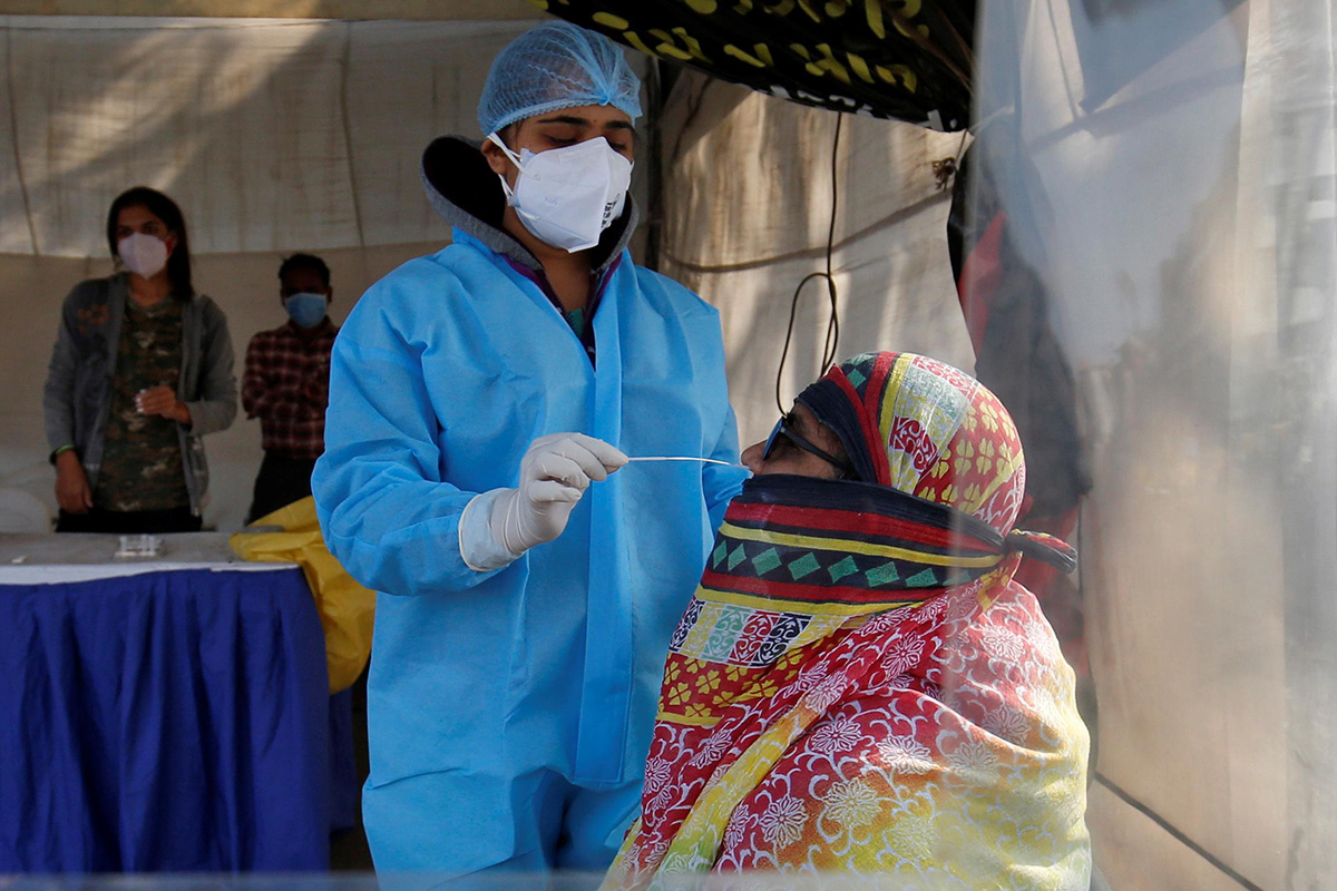 A healthcare worker collects a swab sample from a woman during a rapid antigen testing campaign for the coronavirus disease (COVID-19), in Ahmedabad, India, on 27 January 2021.