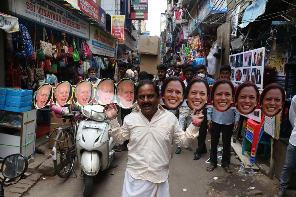 A man wears cut-outs of US President-elect Joe Biden and Vice President-elect Kamala Harris and walks on a street in Chennai, India, on 20 January 2021.