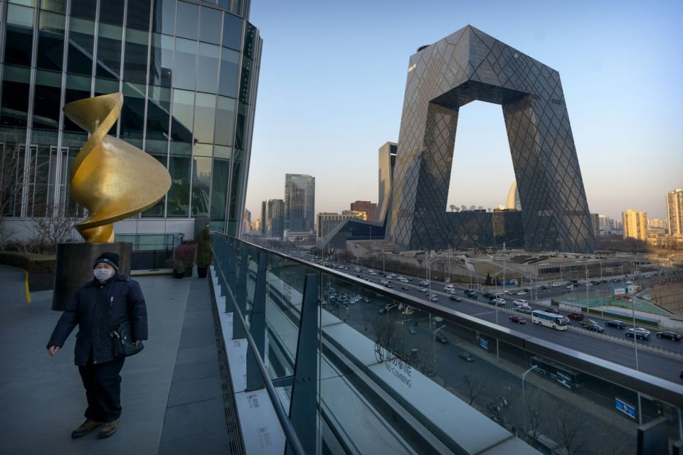 In this 4 Febrruary 2021, file photo, a man wearing a face mask to protect against the spread of the coronavirus walks along an observation deck near the CCTV Headquarters building, the home of Chinese state-run television network CCTV and its overseas arm CGTN, in Beijing. China has banned the BBC World News television channel from the few outlets where it could be seen in the country in possible retaliation after British regulators revoked the license of state-owned Chinese broadcaster CGTN.