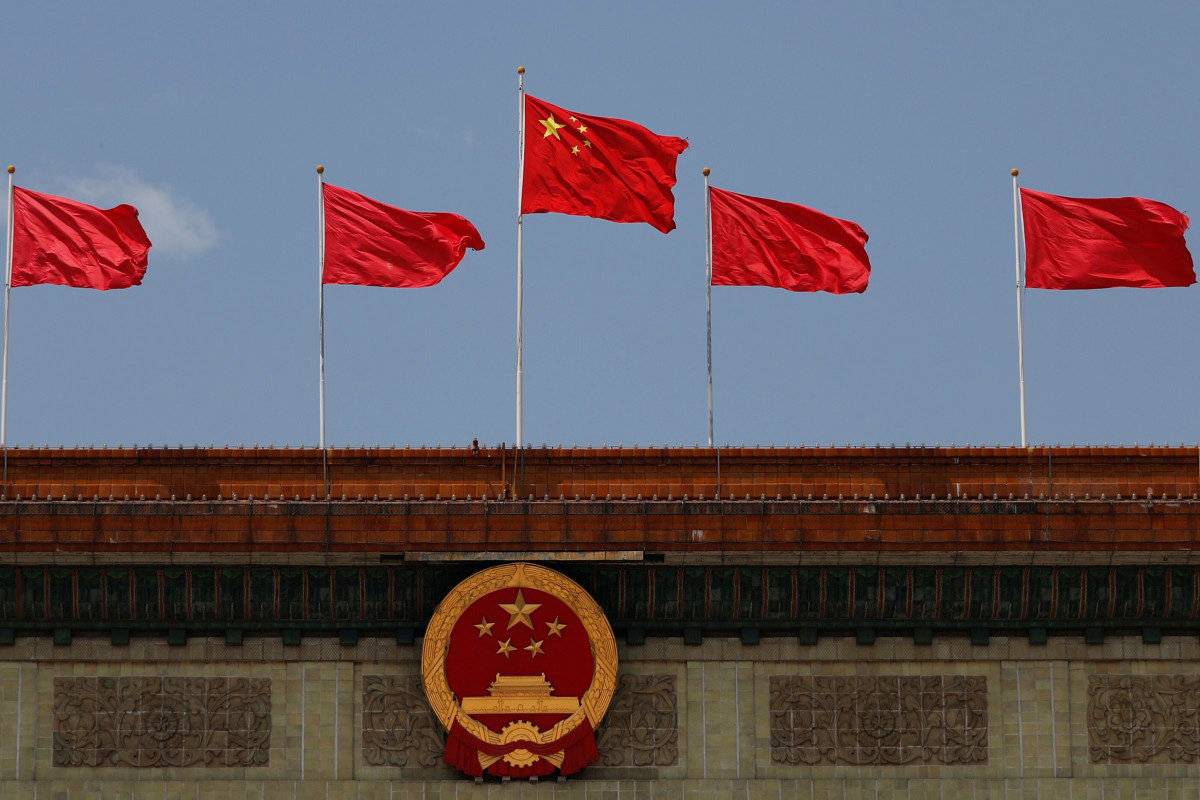 A Chinese flag flutters above the Chinese national emblem at the Great Hall of the People after the opening session of the National People's Congress (NPC) in Beijing, China, on 22 May 2020.