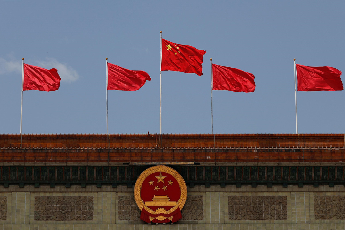 A Chinese flag flutters above the Chinese national emblem at the Great Hall of the People after the opening session of the National People's Congress (NPC) in Beijing, China, on 22 May 2020.