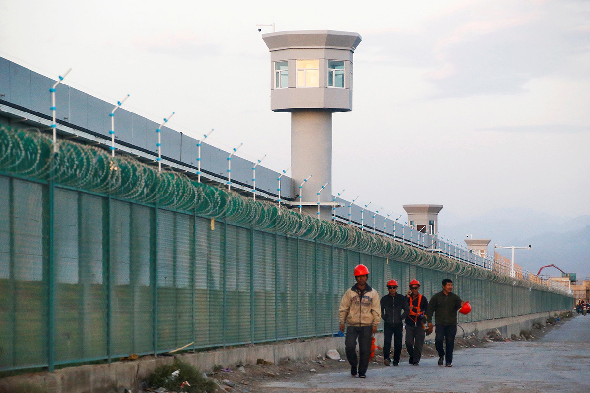 Workers walk by the perimeter fence of what is officially known as a vocational skills education centre in Dabancheng in Xinjiang Uyghur Autonomous Region, China, on 4 September 2018.
