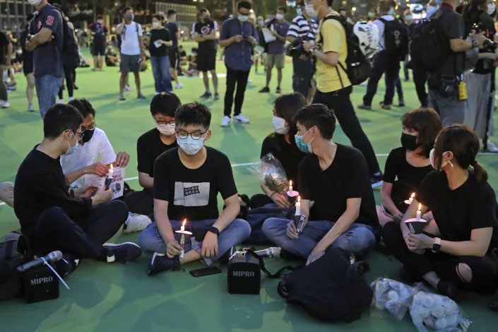 In this 4 June 2020 photo, Hong Kong democracy activist Joshua Wong, second left, holds candle as he joins others for a vigil to remember the victims of the 1989 Tiananmen Square Massacre at Victoria Park in Hong Kong. Wong will face an additional 10 months in jail for participating in an unauthorized Tiananmen vigil held last year to commemorate the 1989 crackdown on protesters in Beijing, as Hong Kong authorities continue tightening control over dissent in the city.