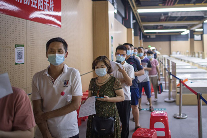 People wearing face masks line up to receive the COVID-19 vaccines at a vaccination site in Jiangxia District in Wuhan, central China's Hubei Province, on 9 June 2021.