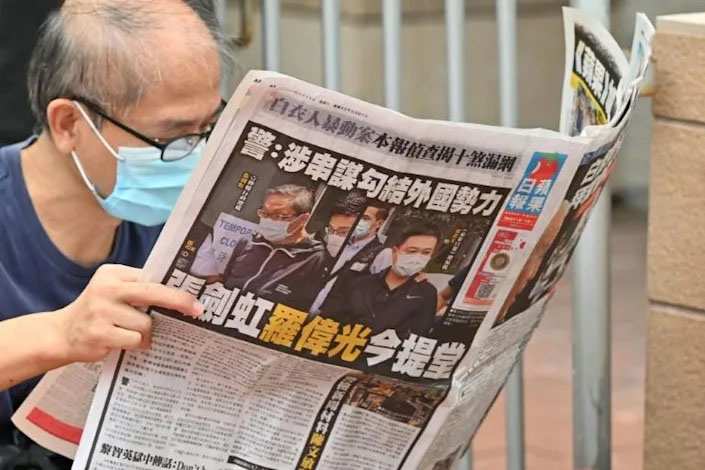 A supporter reads a copy of the Apple Daily newspaper outside a court in Hong Kong.