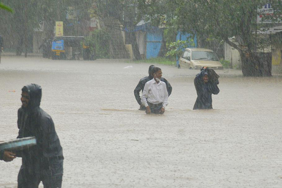 People wade through floodwaters in Kolhapur, in the western Indian state of Maharashtra, on 23 July 2021. Landslides triggered by heavy monsoon rains hit parts of western India, killing more than 30 people and leading to the overnight rescue of more than 1,000 other people trapped by floodwaters, officials said Friday.