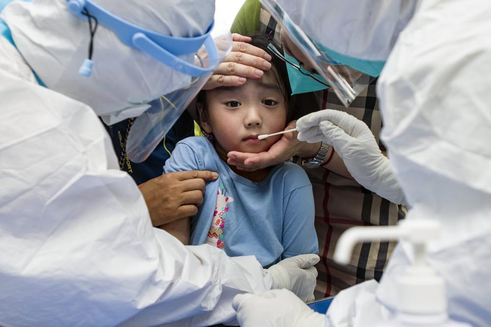 A child reacts to a throat swab during mass testing for COVID-19 in Wuhan in central China's Hubei province on 3 August 2021. The coronavirus’s delta variant is challenging China’s costly strategy of isolating cities, prompting warnings that Chinese leaders who were confident they could keep the virus out of the country need a less disruptive approach.