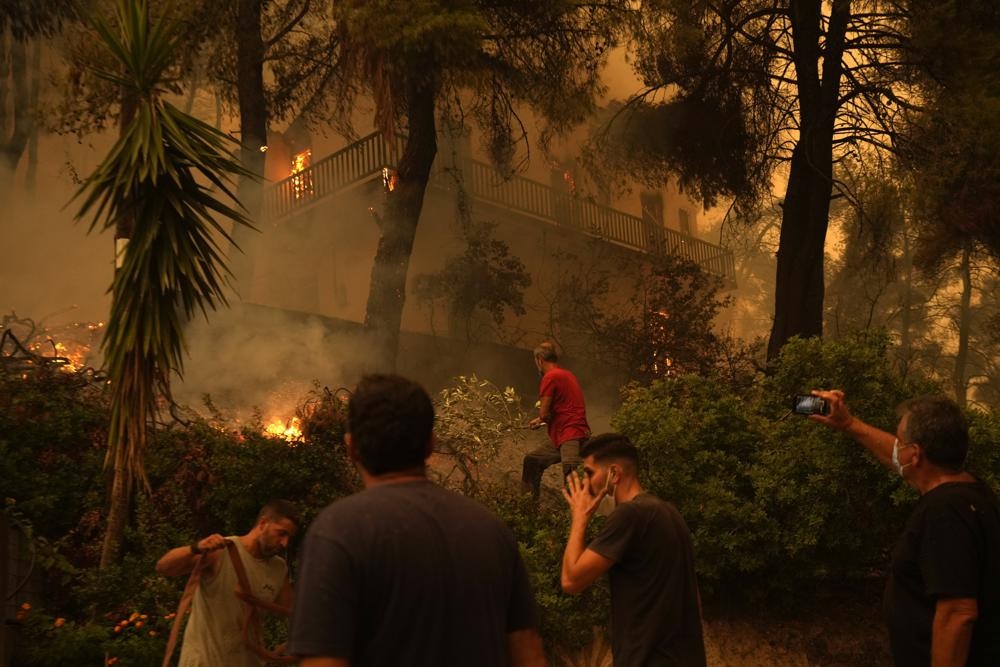 Flames burn a house at Pefki village on Evia island, about 189 kilometres (118 miles) north of Athens, Greece, on 8 August 2021. Pillars of billowing smoke and ash are blocking out the sun above Greece's second-largest island as a days-old wildfire devours pristine forests and triggers more evacuation alerts.